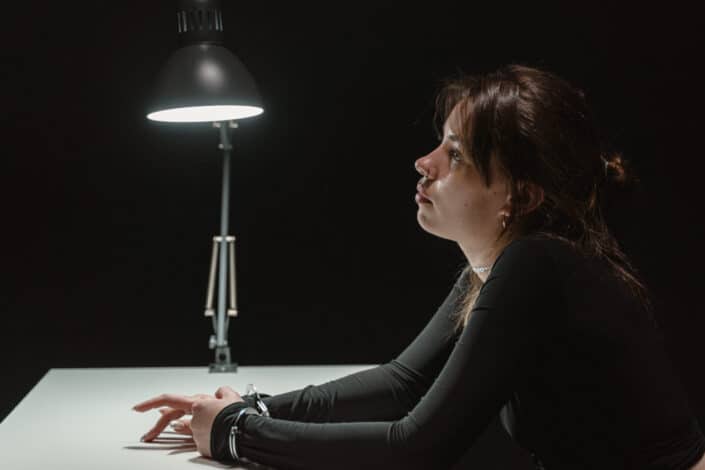 A woman in handcuffs inside an interrogation room