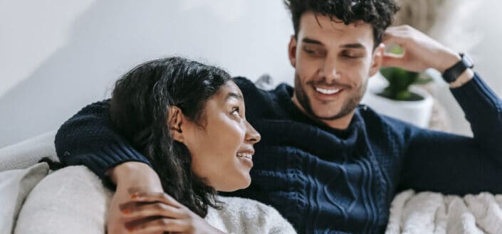 Couple Resting on Couch Under Blanket