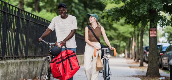 Colleagues from delivery services wheeling bikes after job