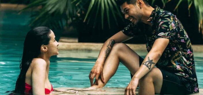 Couple Sitting in a Swimming Pool and Looking Each Other in the Eyes