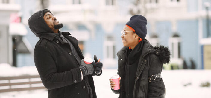 Couple standing outdoors holding their cofffee