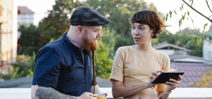 Creative young man and woman talking while using tablet