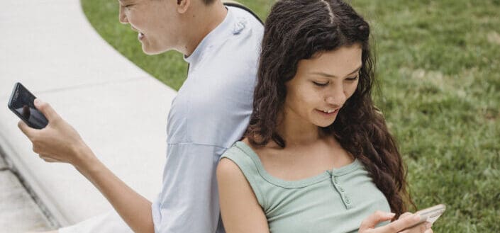 couple chatting on smartphones on street bench