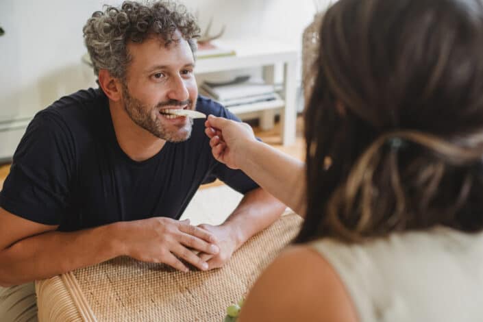 man eating fruit from hand of wife