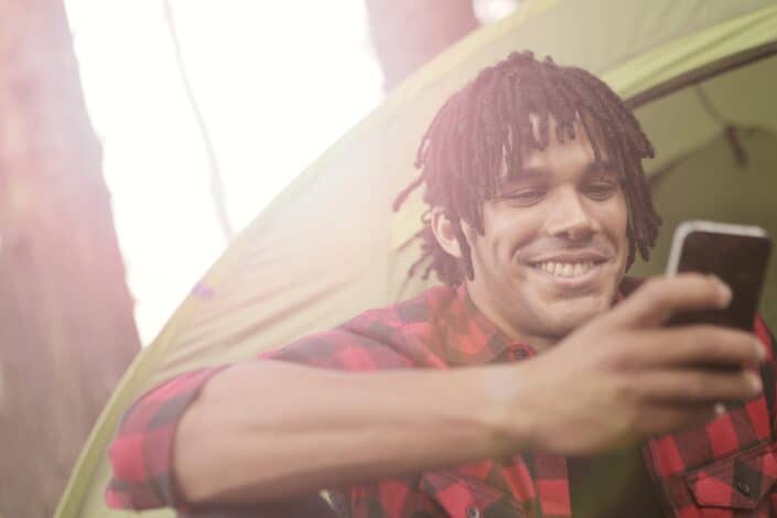 Happy man with dreadlocks using smartphone