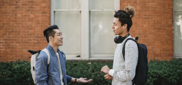 two men talking on sidewalk
