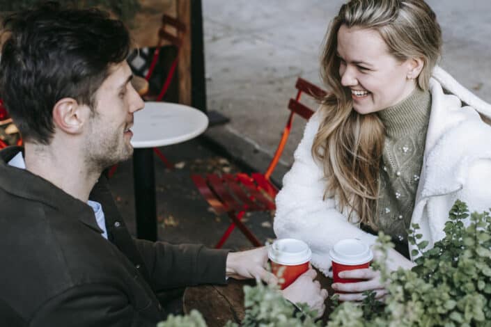 Loving young couple laughing while spending free time together in cafe