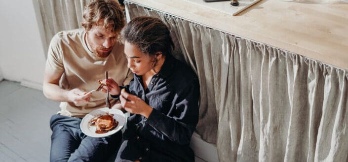 Man and woman eating under kitchen table