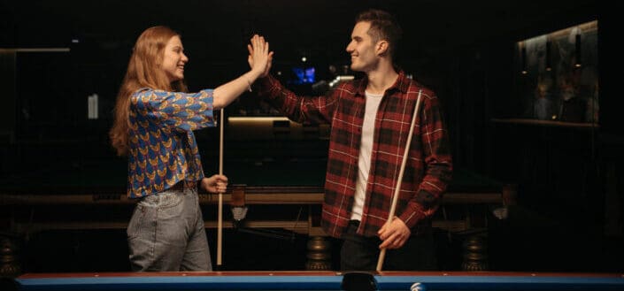 Man and woman standing beside the billiard table