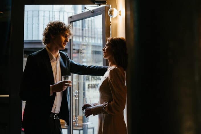 Man in Black Suit Standing on the Doorway With a Woman