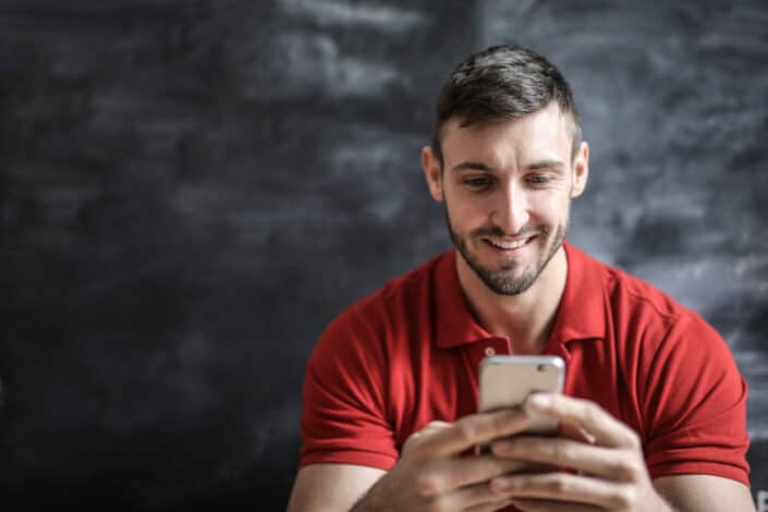 Man in red polo shirt holding gold iphone 6
