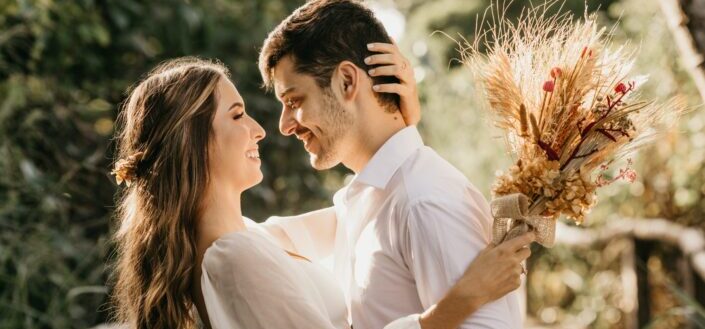 woman in white dress shirt holding brown flower bouquet