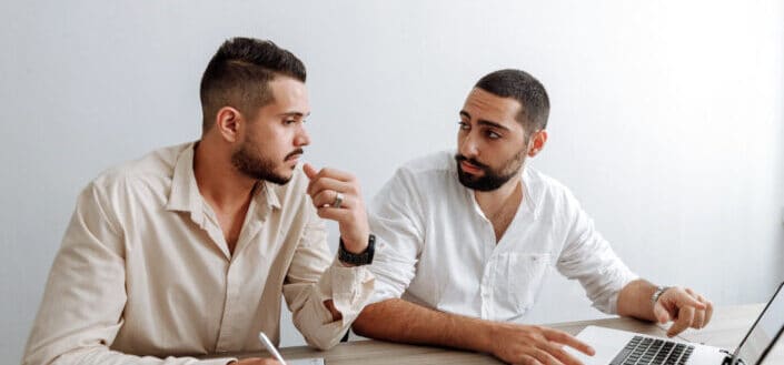 Men sitting by the table with laptop