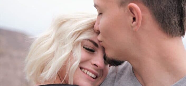 man kisses woman on forehead