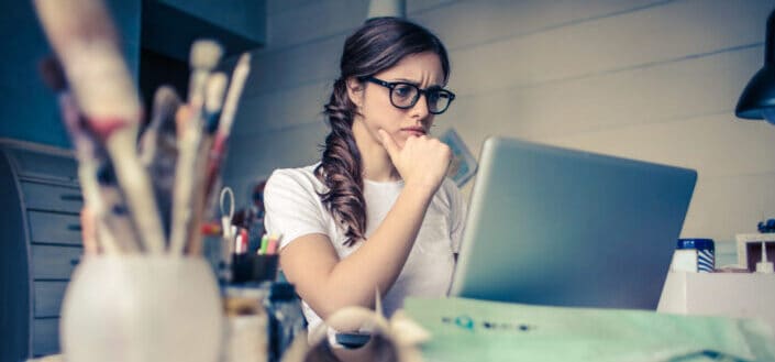 a woman looking at her laptop thinking