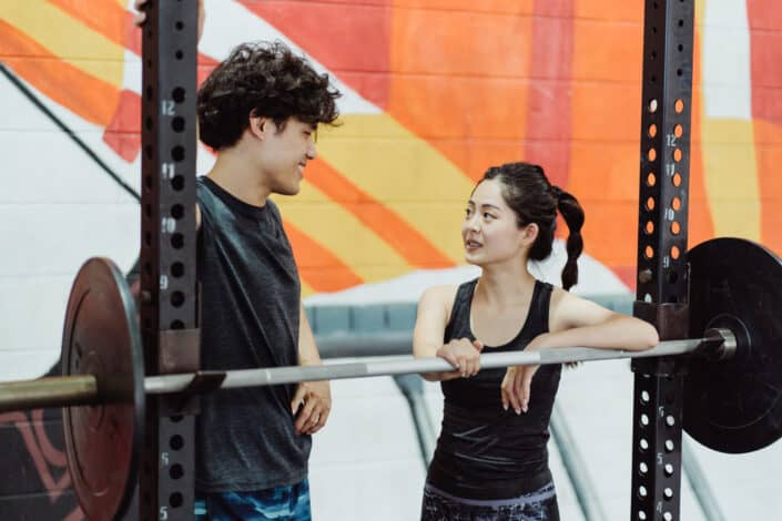 Photograph of a woman in a black tank top looking at a man with curly hair