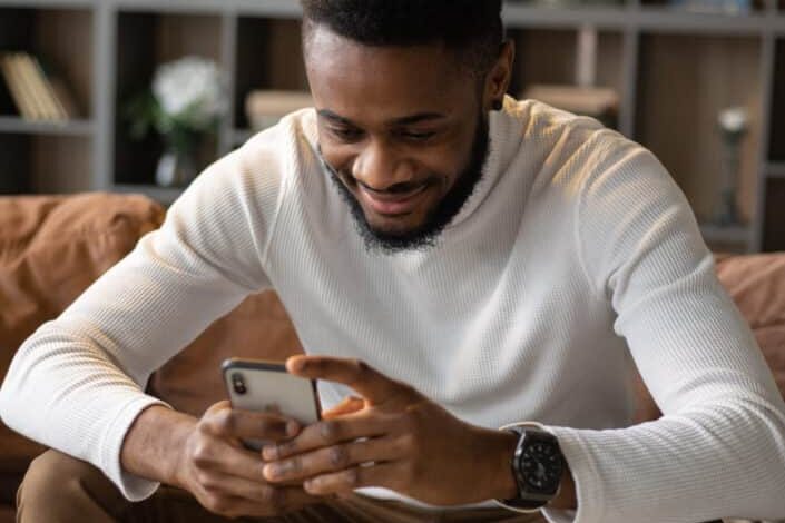 man using smartphone while sitting on sofa