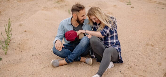 Smiling man and woman sitting on sand beach