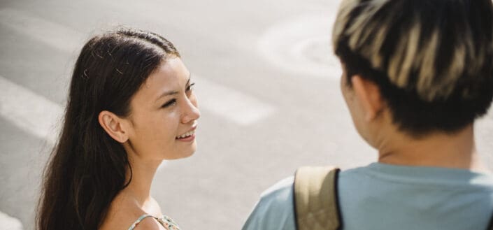 Smiling young girlfriend standing on crosswalk with boyfriend