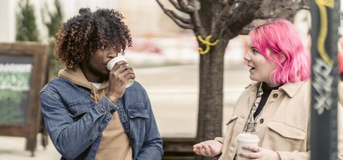 man and woman talking while drinking coffee