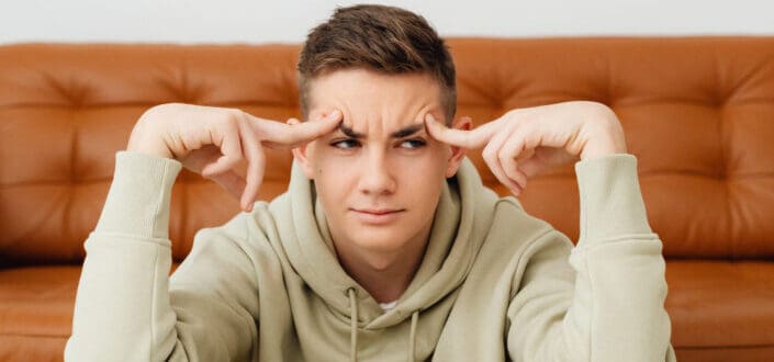 Teenage boy sitting in front of open textbooks looking confused