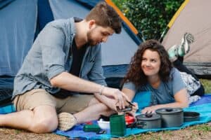 Truth or dare questions for boyfriend - Happy young couple preparing lunch during camping in forest - featured