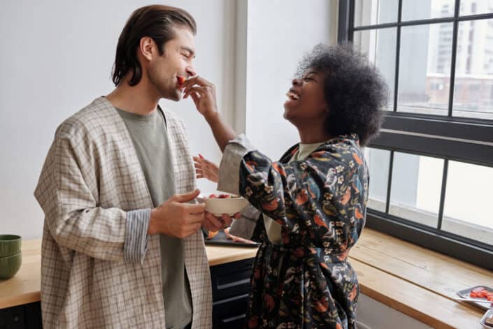 Woman feeding strawberries to a man laughing