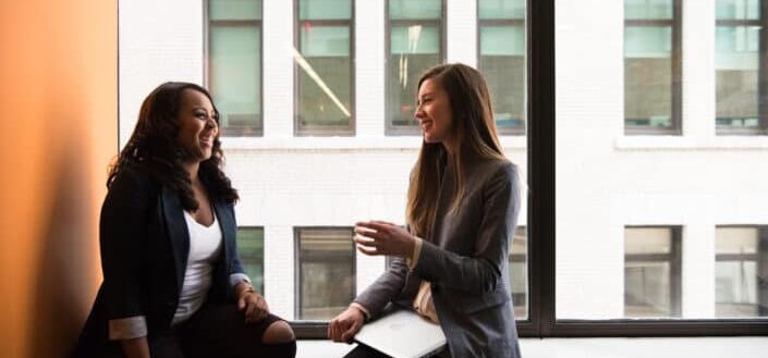 women sitting near black full glass panel window