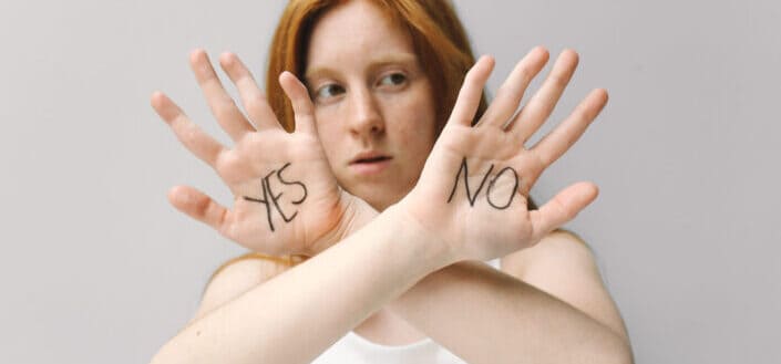 Woman in white shirt covering her face with her hands