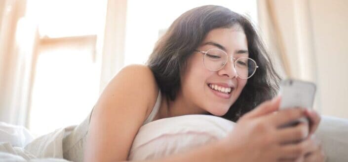 Woman in white tank top lying on bed