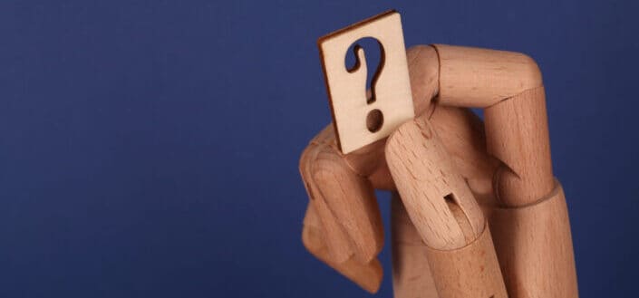 a wooden hand holding a question mark symbol