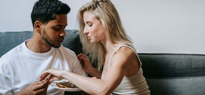 A couple eating together on a couch