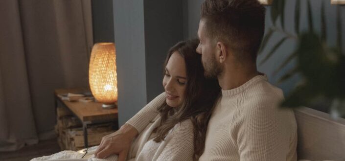 A romantic couple sitting on bed next to each other