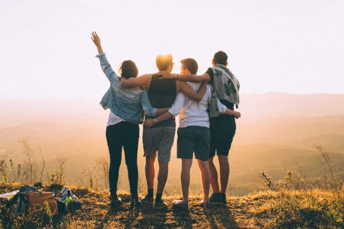 Friends standing together at sunset in mountains