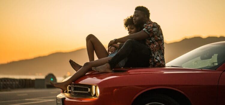 man and woman sitting on the car hood