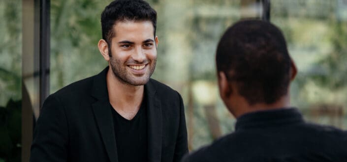Cheerful diverse male friends having coffee break in outdoor cafe