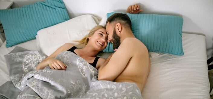 Couple cuddling in bed under covers