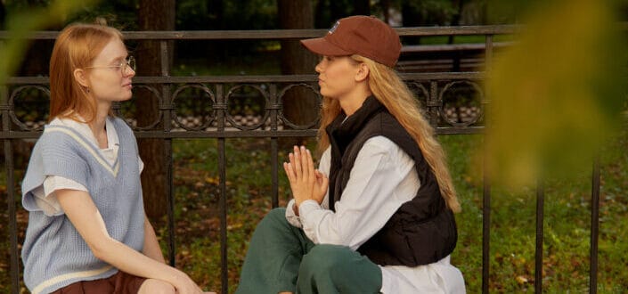 Friends chatting while sitting on a wooden bench