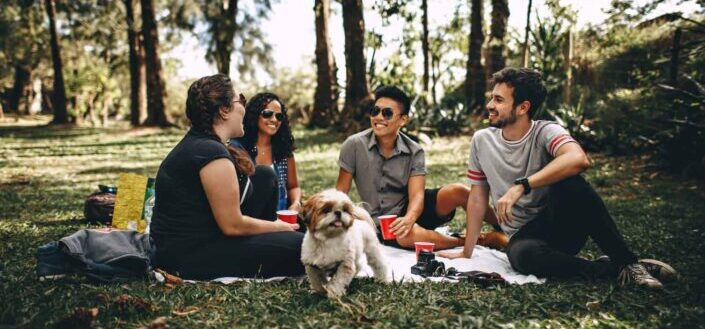Group of people sitting on white mat on grass field