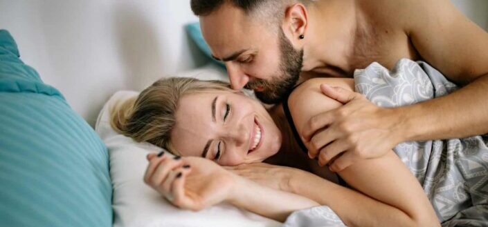 Happy couple cuddling in bed in morning