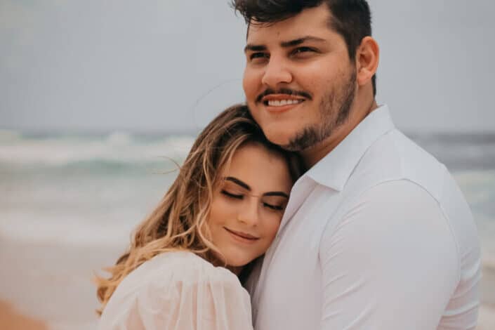 Happy couple hugging on sandy beach against sea