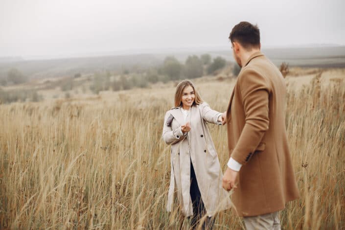 couple holding hands and enjoying autumn day in meadow
