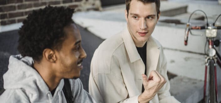 Happy young diverse guys talking on city street