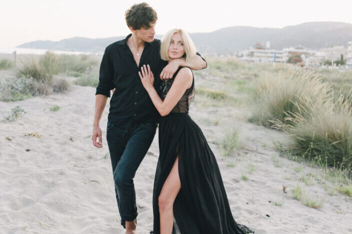 Man in black long sleeves hugging woman in black dress