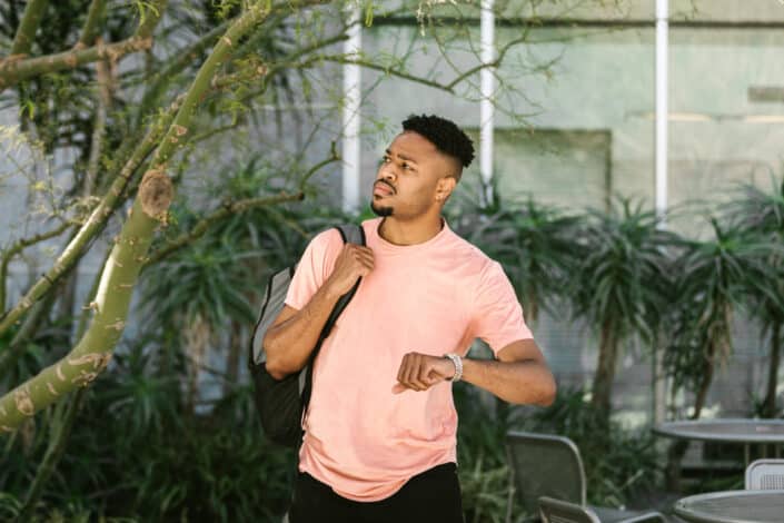 Man in pink crew neck t shirt standing near green tree
