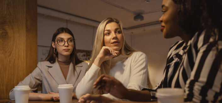 three ladies talking while drinking coffee
