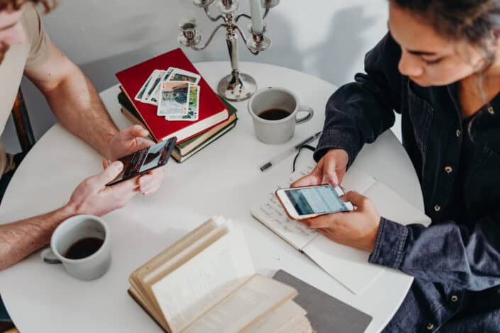 Two people using their phones on a round table
