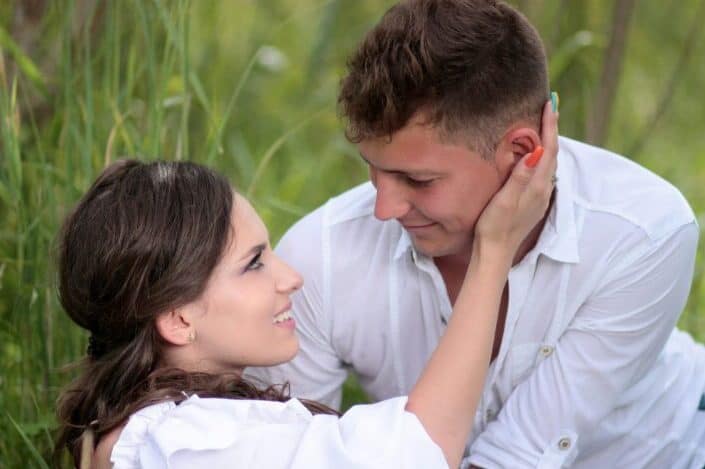 couple laying down on a grass field