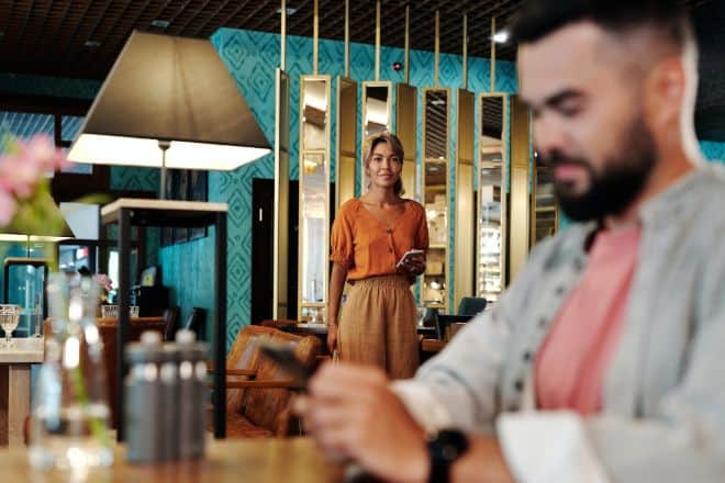 woman on phone looking at man - Things To Do On Dates