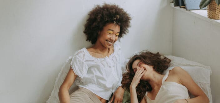 Two women talking and laughing on bed